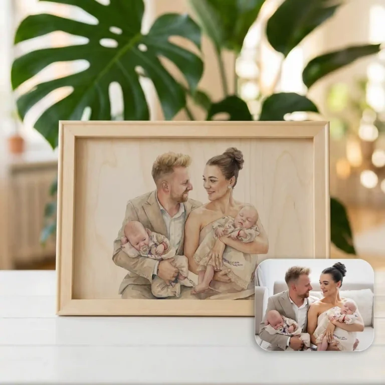 A portret de familie botez înrămat surprinde un cuplu zâmbind alături de doi bebeluși, cu fotografia originală a familiei așezată lângă tablou pe o masă albă. În fundal se distinge vag o plantă verde mare.